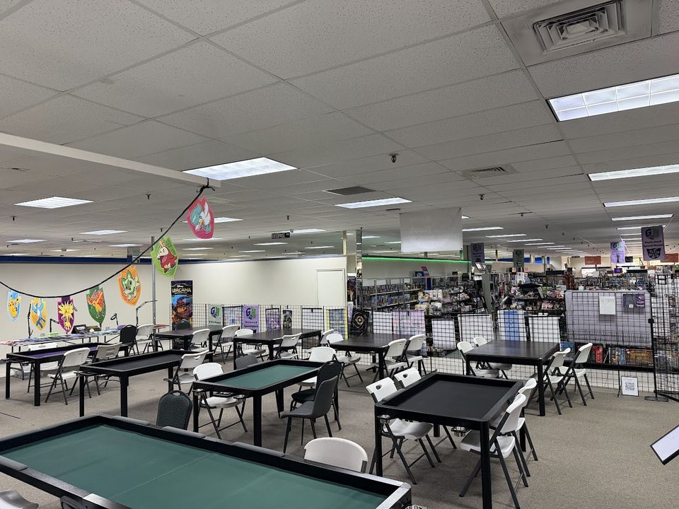 Game Nook's play space: rows of Box King gaming tables and chairs on Geek Valhalla's open floor, Pokémon banners on the wall and the shop's shelves beyond.